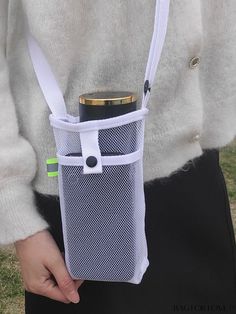 a person holding a cell phone in a mesh bag with a bottle attached to it