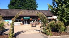 the entrance to a restaurant with an arch over it's entrance and trees surrounding it