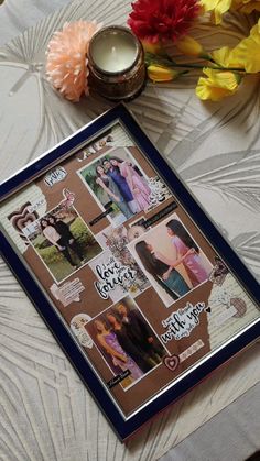 a photo frame sitting on top of a table next to flowers and a lit candle