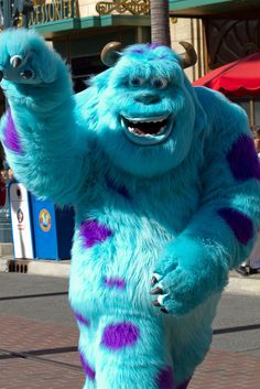 a man dressed in blue and purple poses for the camera while holding his hand up