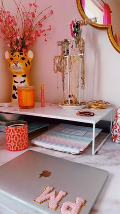 an open laptop computer sitting on top of a white desk next to a vase with flowers