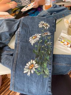 a pair of jeans with flowers painted on them