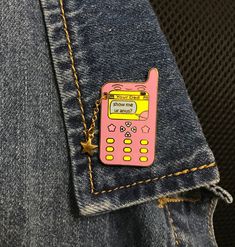 a pink cell phone sitting in the pocket of someone's jean pants with yellow stitching