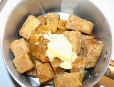 a metal bowl filled with cubed food on top of a stove