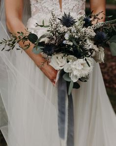 a bride holding a bouquet of white and blue flowers