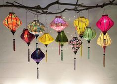 many colorful lanterns hanging from a tree branch