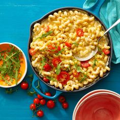 a skillet filled with macaroni and cheese next to bowls of tomato sauce