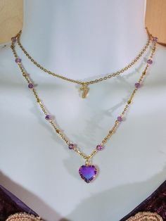 a purple heart shaped necklace on a mannequin's neck with gold chains