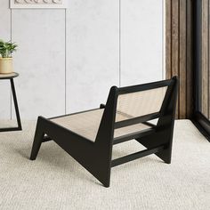 a black chair sitting on top of a carpeted floor next to a table with a potted plant