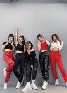 the girls are posing in front of a gray wall and one girl is holding her hand up