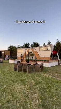 an image of a house in the middle of a field with chairs and tables around it