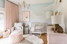 a baby's room with pink and white decor, including a crib, rocking chair, rugs, lamps, and pictures on the wall