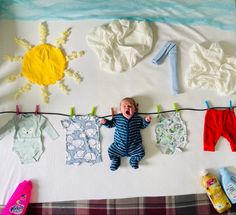 a baby laying on top of a bed next to clothes