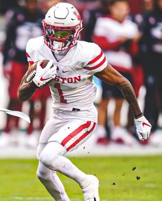 a football player running with the ball in his hand and people watching from the stands behind him