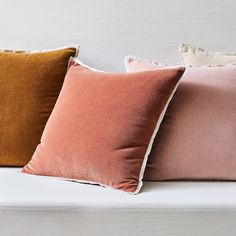 three different colored pillows sitting on top of a white couch