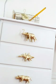 three gold rhinoceros on white drawers in a bedroom