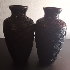 two black vases sitting next to each other on a table