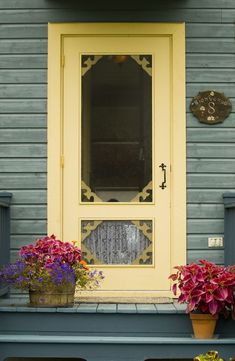 a blue house with yellow door and flower pots