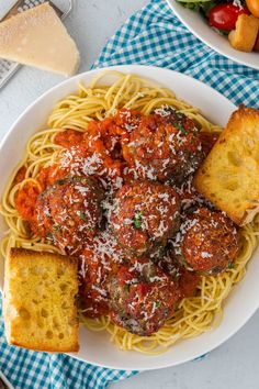 pasta with meatballs and parmesan bread on a plate next to a salad