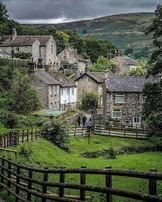 the village is surrounded by lush green hills and trees, with houses in the background