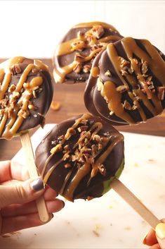 chocolate covered donuts with caramel drizzle and pecans are being held on a stick