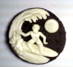 a cookie with white frosting on it and a silhouette of a man surfing in the ocean