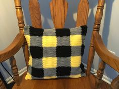 a crocheted pillow sitting on top of a wooden chair