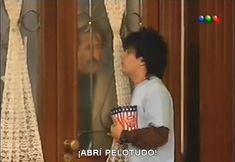 a young man holding a popcorn cup in front of a window with an ad on it