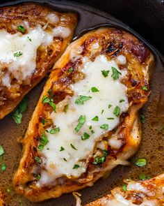 two pieces of chicken covered in cheese and parsley on top of a skillet