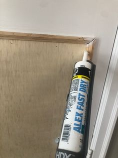 a tube of glue sitting on top of a wooden door frame next to a wall