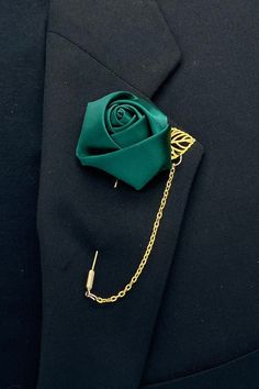 a lapel pin with a green rose on it's lapel, attached to a black suit jacket