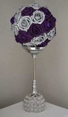 a silver vase with purple and white flowers in it