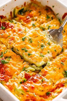 a casserole dish with zucchini and cheese in it, being lifted by a spatula