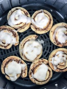 several cinnamon rolls sitting on top of an open frying pan filled with white icing