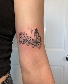 a woman's arm with a butterfly and dominos tattoo on the left forearm