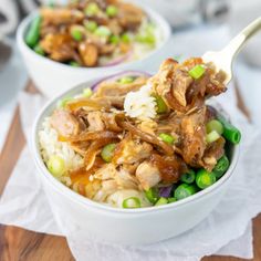 two bowls filled with meat and rice on top of a wooden table