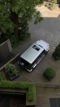 a car parked on the side of a road next to some bushes and trees in front of a building