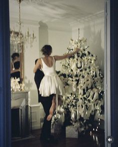 a woman standing next to a christmas tree