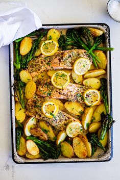 a pan filled with chicken, potatoes and asparagus on top of a table