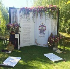 an outdoor ceremony setup with flowers and greenery on the wall, surrounded by other decorations