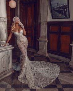 a woman in a wedding dress standing next to a marble column with a large white ball hanging from it's side