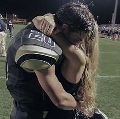 a football player hugging his girlfriend on the sidelines