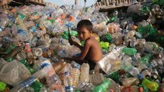 a young boy sitting in a pile of plastic bottles