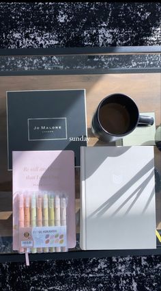 a cup of coffee, notebooks and other items sitting on a table next to each other