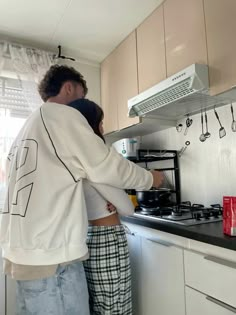 a man and woman are cooking in the kitchen