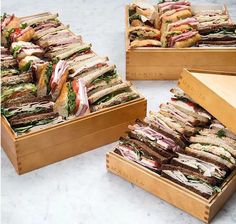 several wooden boxes filled with sandwiches on top of a white countertop next to each other