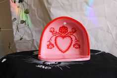 a red heart shaped dish sitting on top of a table