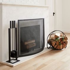 a fire place with logs and a basket on the floor next to it in front of a fireplace