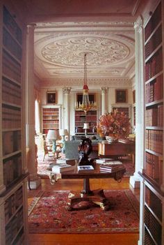 a room with many bookshelves and a table in the middle, along with a chandelier