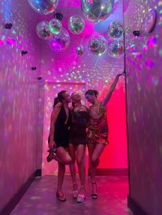 two women are standing in front of some disco balls and pink lights on the ceiling